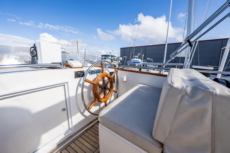 Vesper Yacht Photos Pics 1990 Grand Banks Sedan boat helm with wooden steering wheel and cushioned seat.