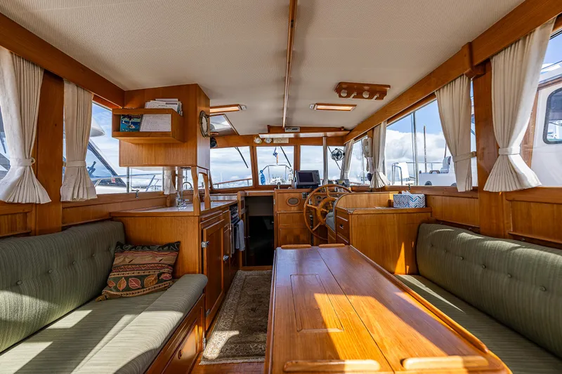 Vesper Yacht Photos Pics Interior of a 1990 Grand Banks Sedan yacht with wooden furnishings and green seating.