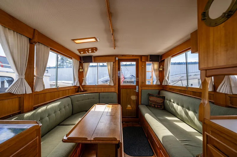 Vesper Yacht Photos Pics Interior of a 1990 Grand Banks Sedan with wooden furnishings and green cushioned seating.