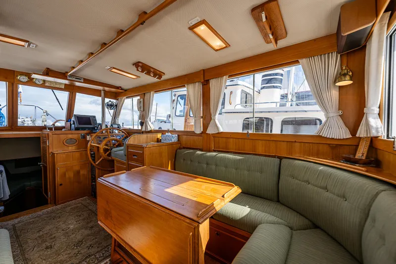 Vesper Yacht Photos Pics 1990 Grand Banks Sedan interior with wooden furnishings and green upholstery.