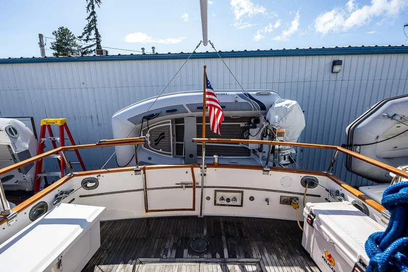 Vesper Yacht Photos Pics 1990 Grand Banks Sedan boat stern view with American flag and docked dinghy.