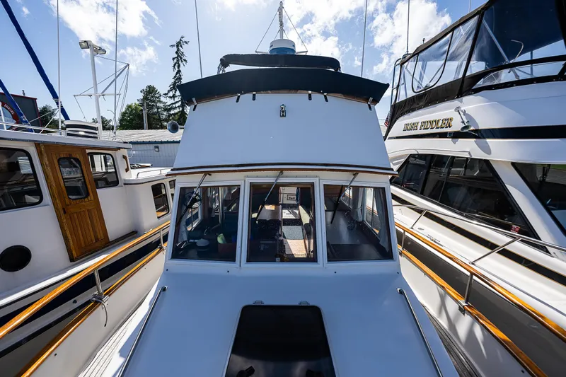Vesper Yacht Photos Pics 1990 Grand Banks Sedan boat docked between other boats under a sunny sky.