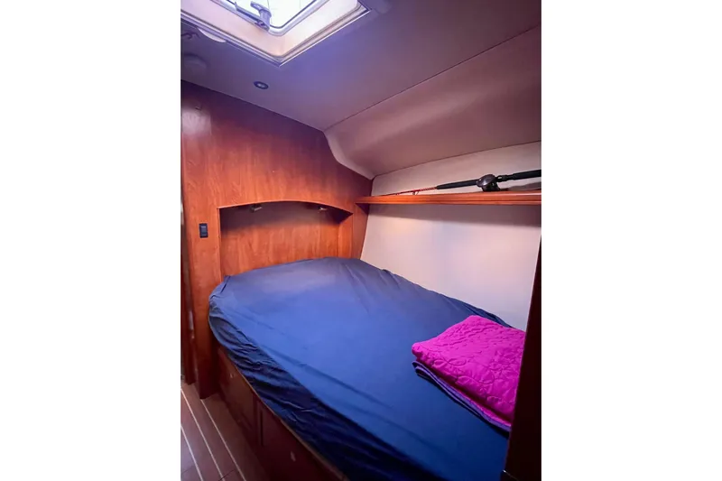  Yacht Photos Pics Cozy cabin interior of 2010 Hunter 45 Deck Salon with blue bedding and wooden finish.