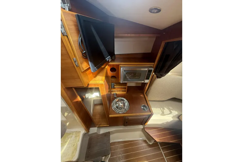  Yacht Photos Pics 2012 Cutwater C-28 interior with kitchenette, featuring a sink, microwave, and wooden cabinetry.