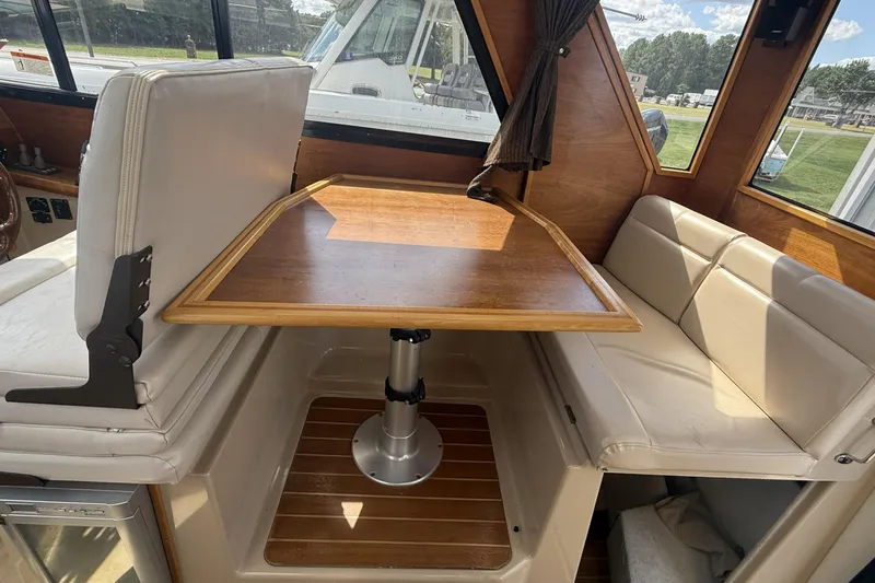  Yacht Photos Pics Interior of a 2012 Cutwater C-28 boat featuring a wooden table and cushioned seating.