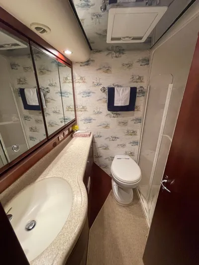  Yacht Photos Pics 2005 Bertram 510 yacht bathroom with sink, toilet, and nautical-themed wallpaper.