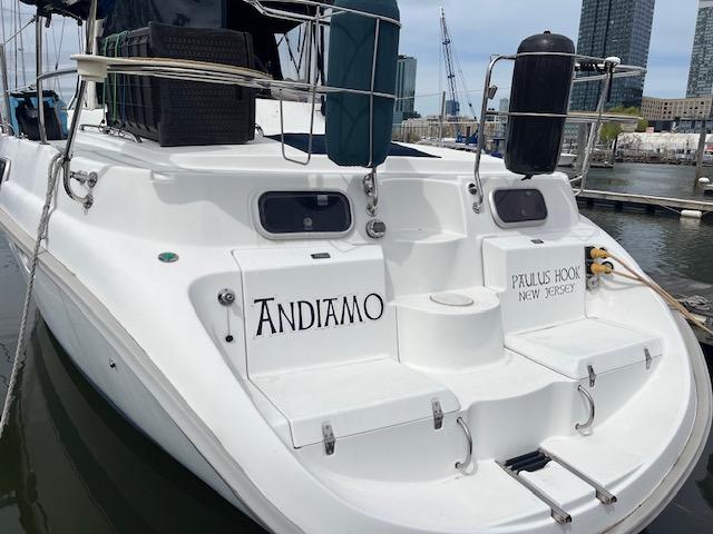 1999 Hunter Passage 450 sailboat docked at marina, featuring "Andiamo" and "Paulus Hook, New Jersey" text.