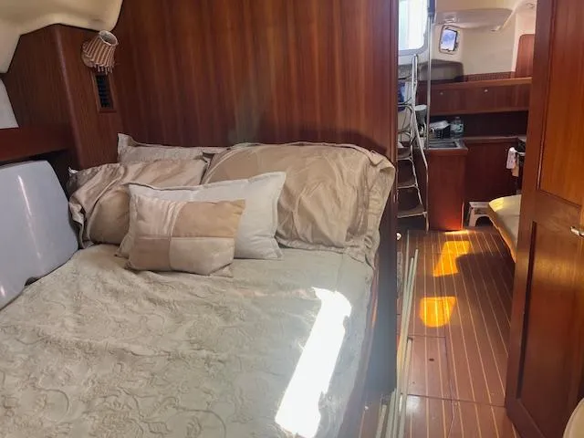 Cozy cabin interior of 1999 Hunter Passage 450 sailboat with bed and wooden furnishings.