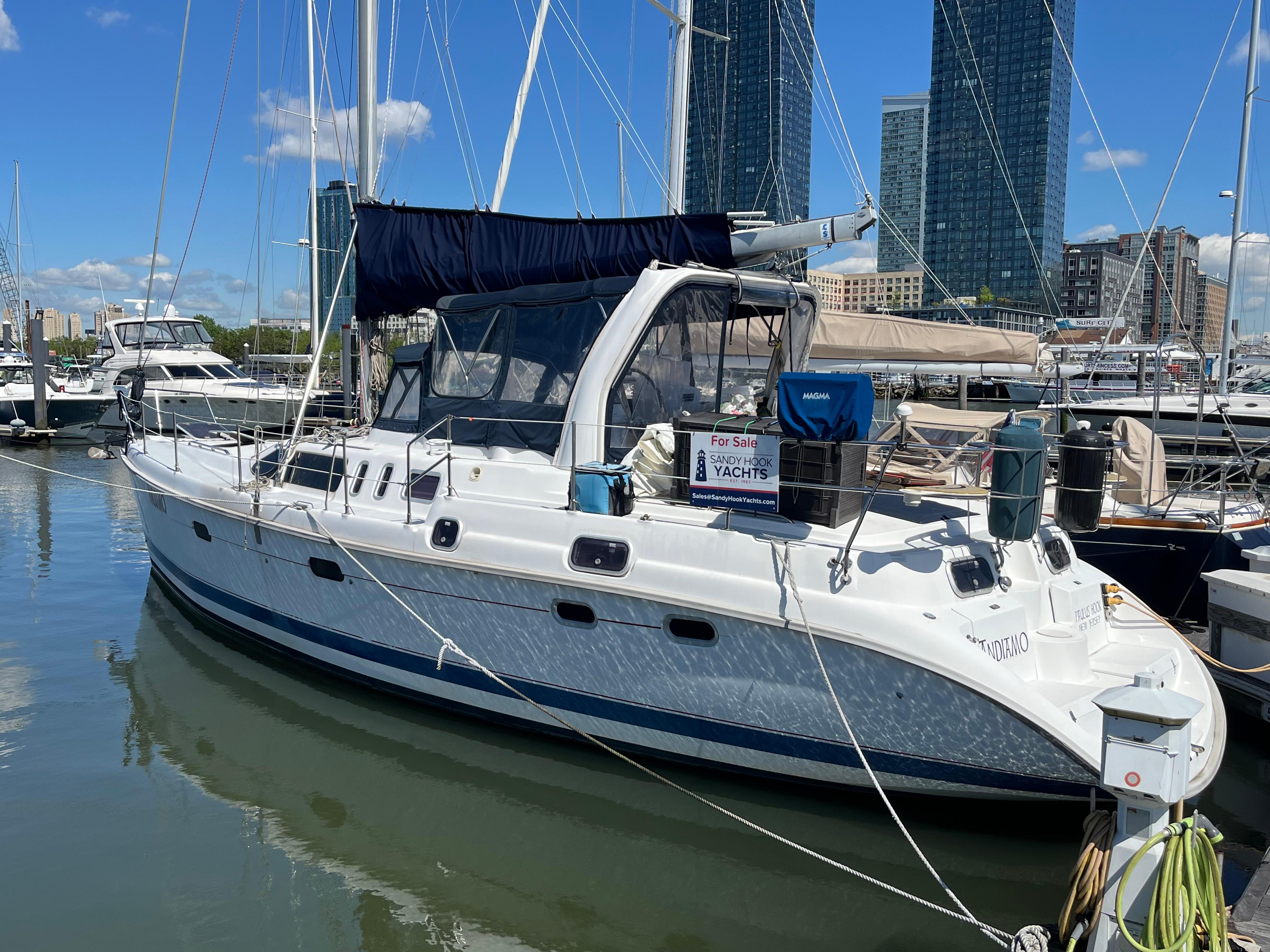 1999 Hunter Passage 450 sailboat docked in marina with city skyline background.