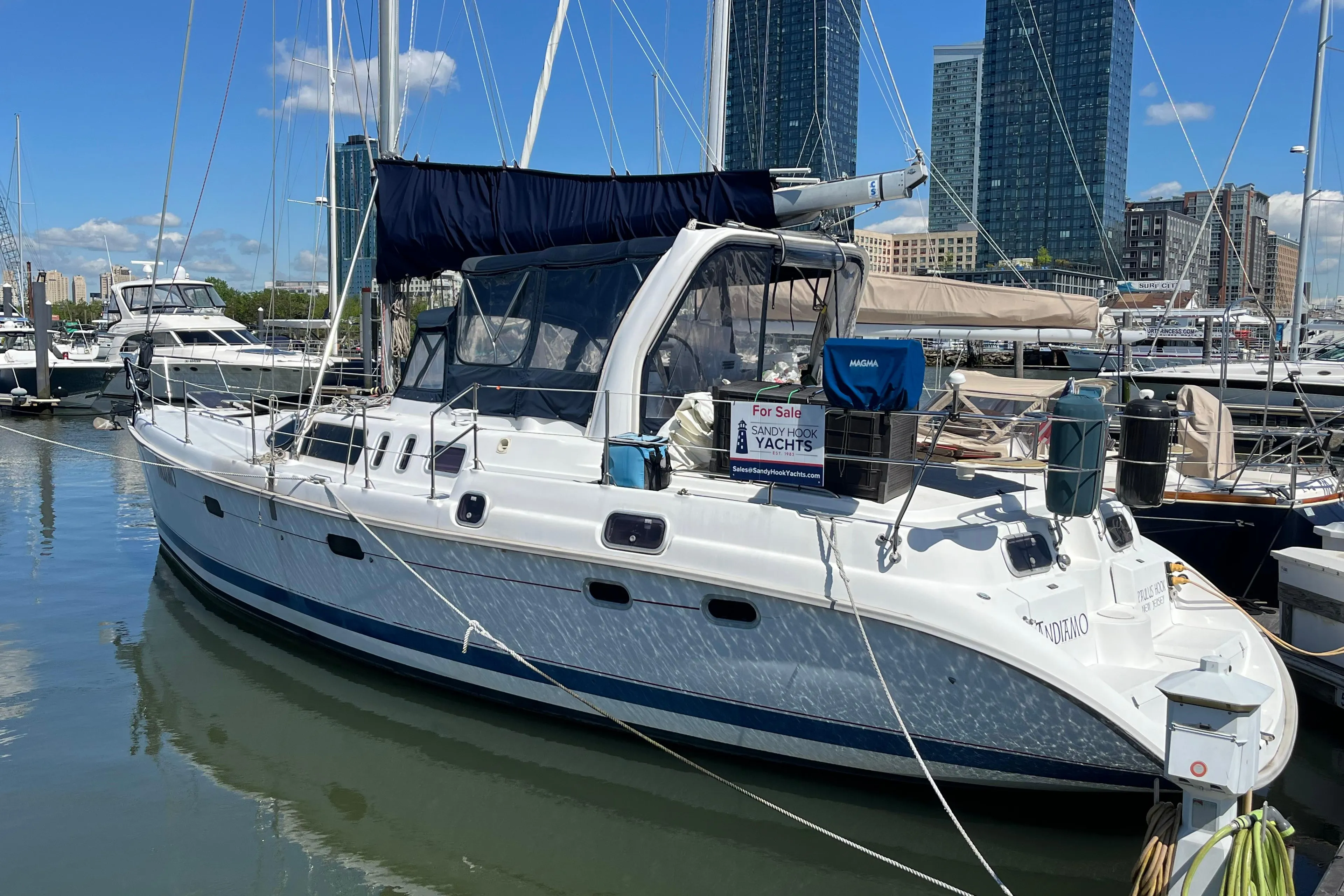 1999 Hunter Passage 450 sailboat docked in marina with city skyline background.