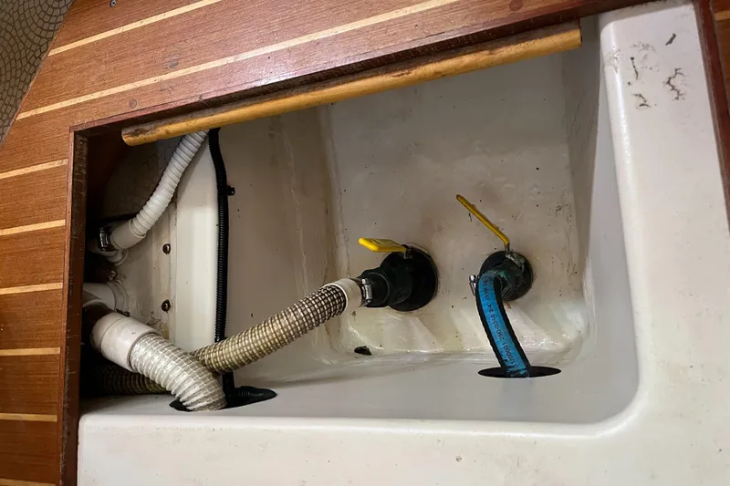  Yacht Photos Pics Interior plumbing of 1999 Hunter Passage 450 sailboat with visible hoses and valves.