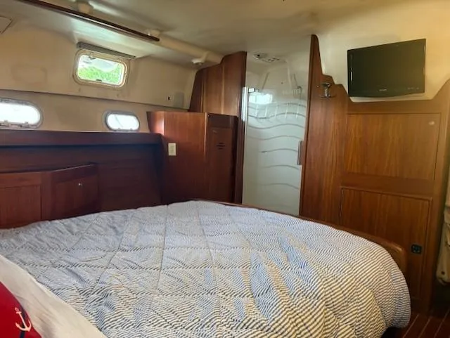  Yacht Photos Pics Cozy cabin interior of 1999 Hunter Passage 450 yacht with bed, wood paneling, and small windows.