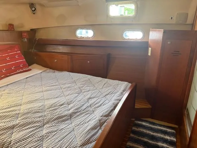  Yacht Photos Pics Cozy cabin interior of 1999 Hunter Passage 450 sailboat with bed and wooden furnishings.