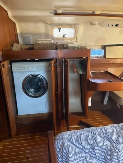  Yacht Photos Pics 1999 Hunter Passage 450 yacht interior with washer, wooden cabinetry, and cozy bedding.