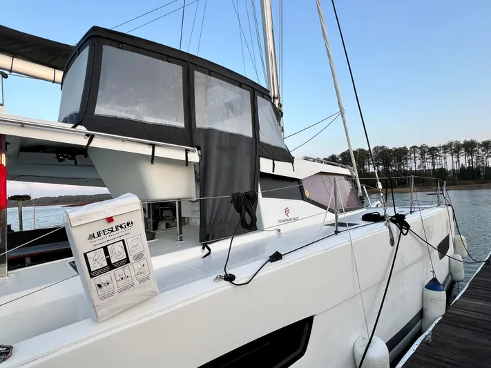 Amihan Yacht Photos Pics 2023 Fountaine Pajot Isla 40 catamaran docked by a serene lake with trees in the background.