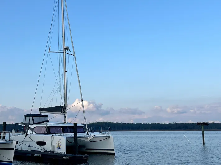Amihan Yacht Photos Pics 2023 Fountaine Pajot Isla 40 catamaran docked on calm water under clear blue sky.