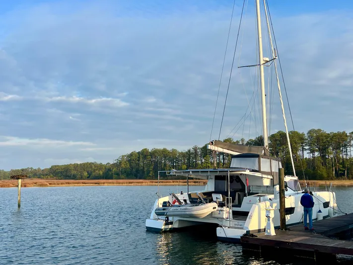 Amihan Yacht Photos Pics 2023 Fountaine Pajot Isla 40 catamaran docked on a serene lake with trees in the background.