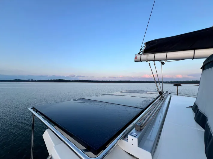 Amihan Yacht Photos Pics 2023 Fountaine Pajot Isla 40 catamaran with solar panels on calm water at sunset.