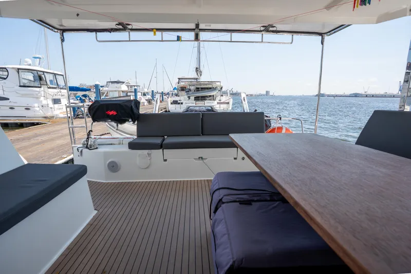 Amihan Yacht Photos Pics 2023 Fountaine Pajot Isla 40 catamaran deck with seating and table, docked at marina.