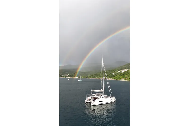 Amihan Yacht Photos Pics 2023 Fountaine Pajot Isla 40 catamaran under a vibrant rainbow on the ocean.