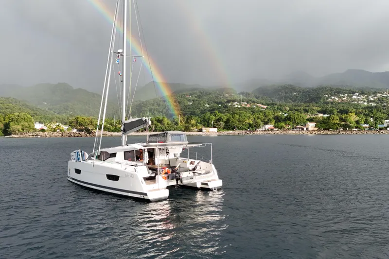 Amihan Yacht Photos Pics 2023 Fountaine Pajot Isla 40 catamaran with rainbow over scenic coastal landscape.