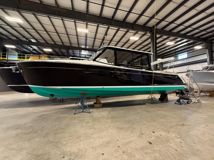 Coco Yacht Photos Pics 2022 MJM 3 boat in a warehouse, black hull with turquoise bottom, on stands.