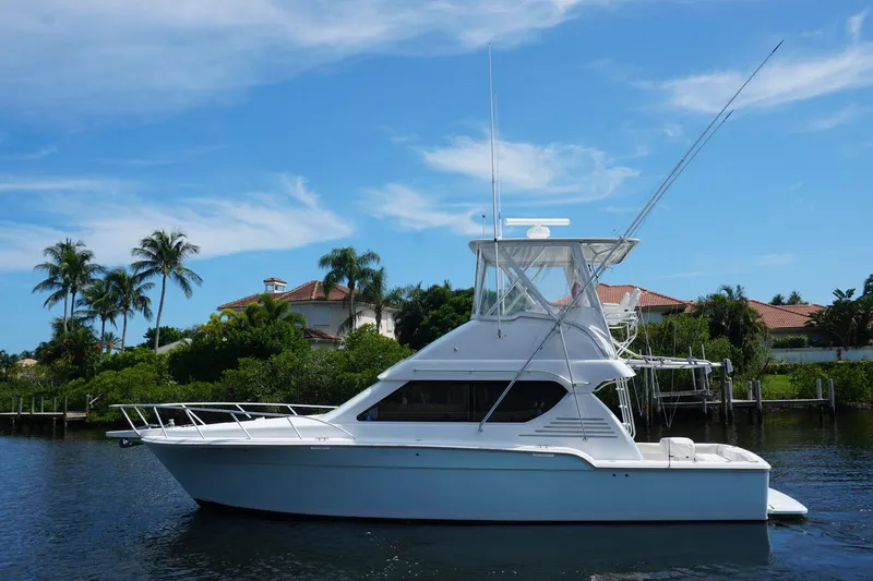 Sea Striker Yacht Photos Pics 2005 Mirage Yachts 40 Convertible boat on calm water, with palm trees and blue sky background.