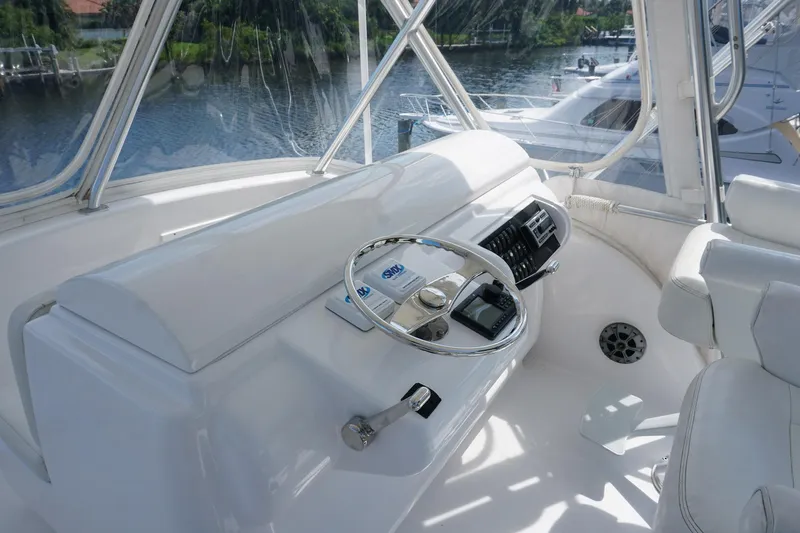 Sea Striker Yacht Photos Pics Helm of 2005 Mirage Yachts 40 Convertible with steering wheel and controls, docked by water.
