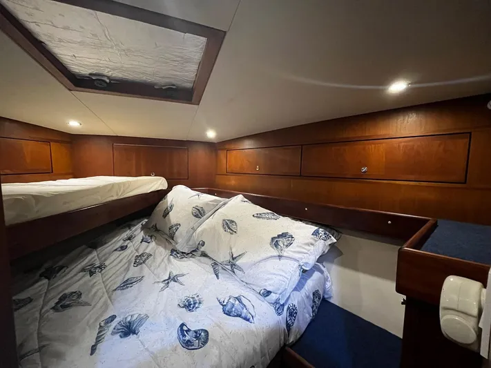 Sea Striker Yacht Photos Pics Cozy cabin interior of 2005 Mirage Yachts 40 Convertible with wooden paneling and nautical bedding.