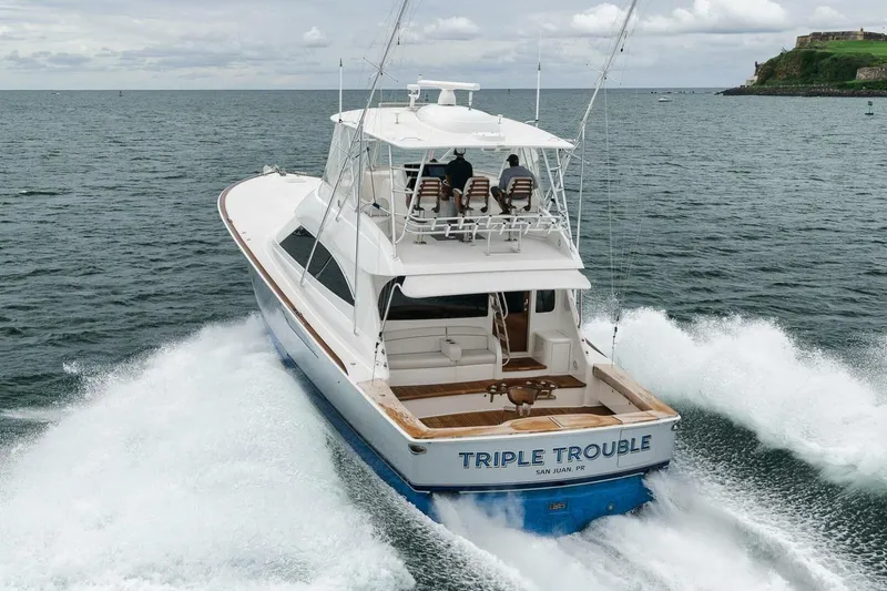 Triple Trouble Yacht Photos Pics 2014 Viking 62 Convertible yacht cruising on open water, rear view.