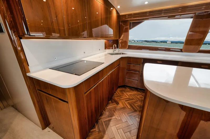 Triple Trouble Yacht Photos Pics Luxurious kitchen interior of 2014 Viking 62 Convertible yacht with wood cabinetry and ocean view.