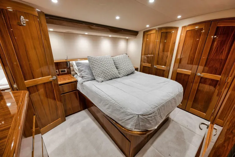 Triple Trouble Yacht Photos Pics Luxurious bedroom interior of 2014 Viking 62 Convertible yacht with wooden cabinetry and cozy bedding.