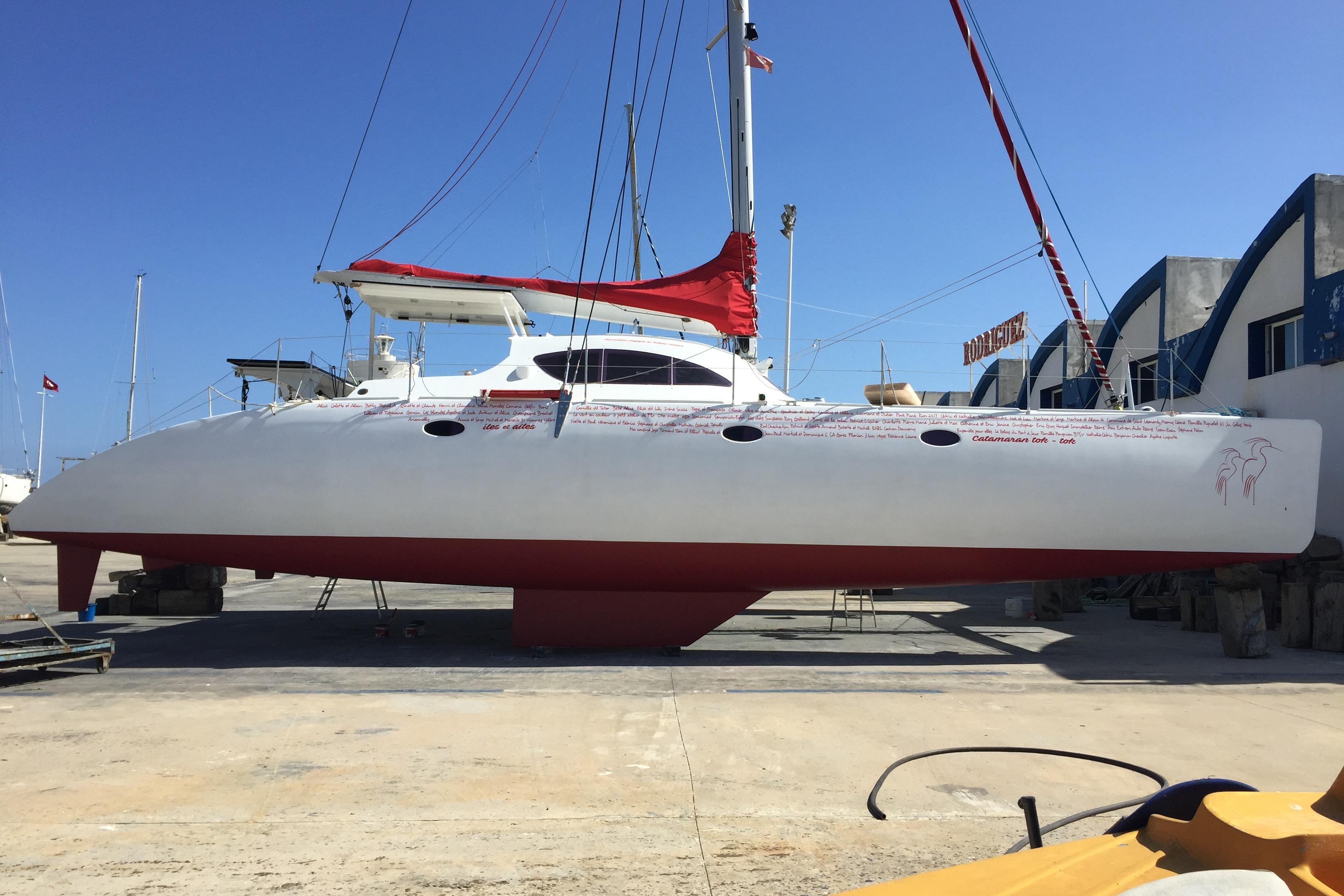 Catamaran Looping 50, 2017 model, docked in a shipyard with red and white design.