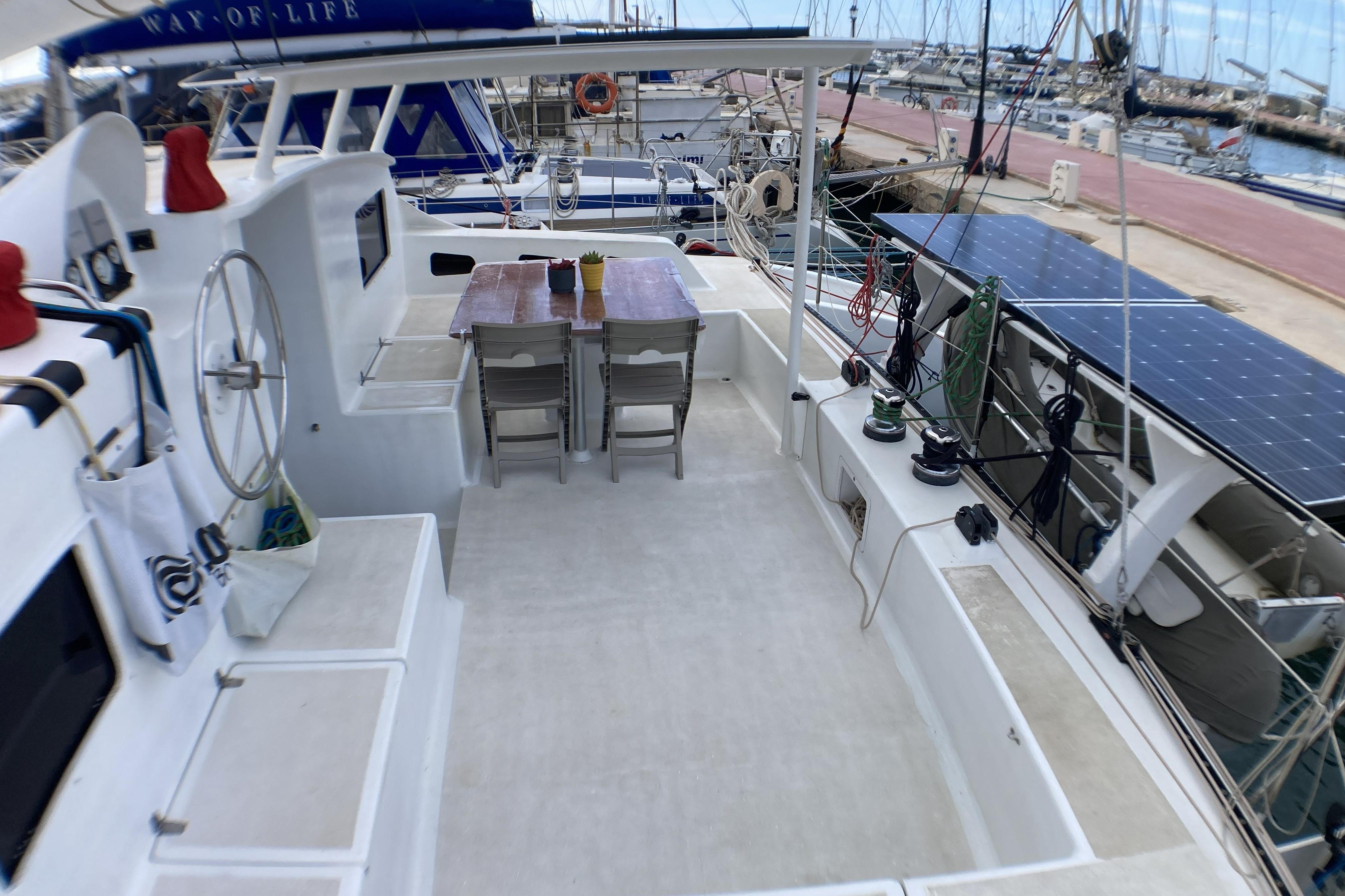 Catamaran deck with dining area, solar panels, and marina view; Looping 50, 2017 model.