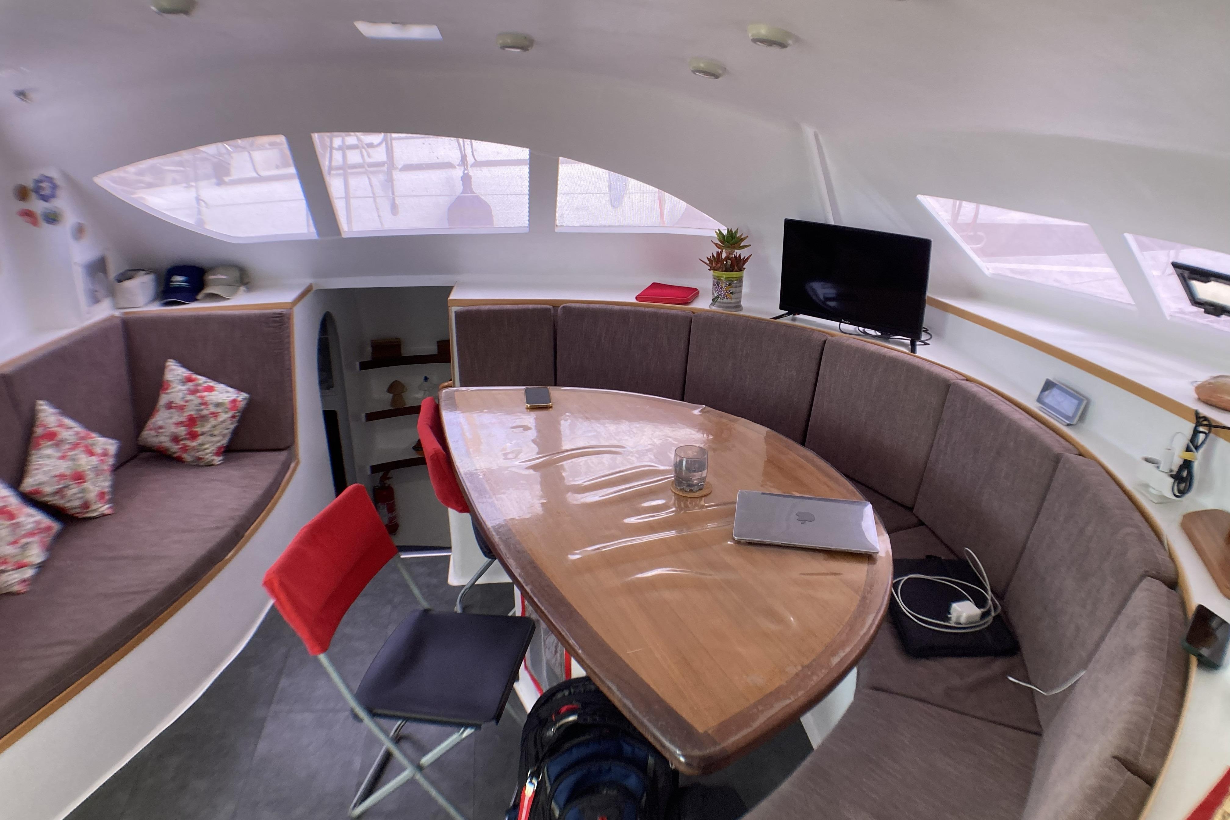 Cozy interior of 2017 Looping 50 catamaran with seating, table, and windows.