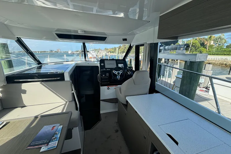 1095-953 Brokerage Josh Yacht Photos Pics 2024 Jeanneau NC Weekender 1095 Fly interior with helm, seating, and waterfront view.