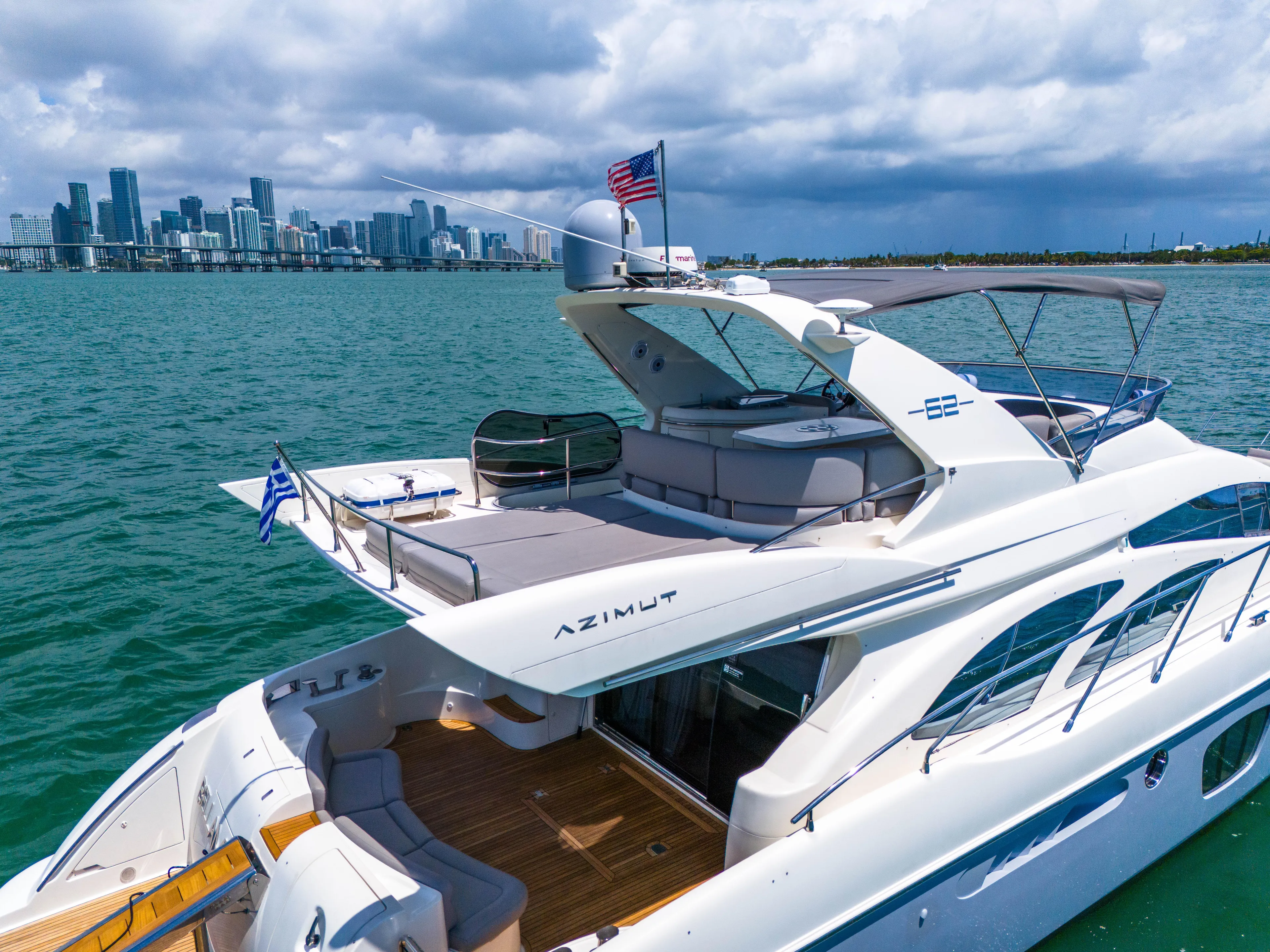 Bellami Too Yacht Photos Pics 2008 Azimut 62E yacht cruising near city skyline under cloudy skies.