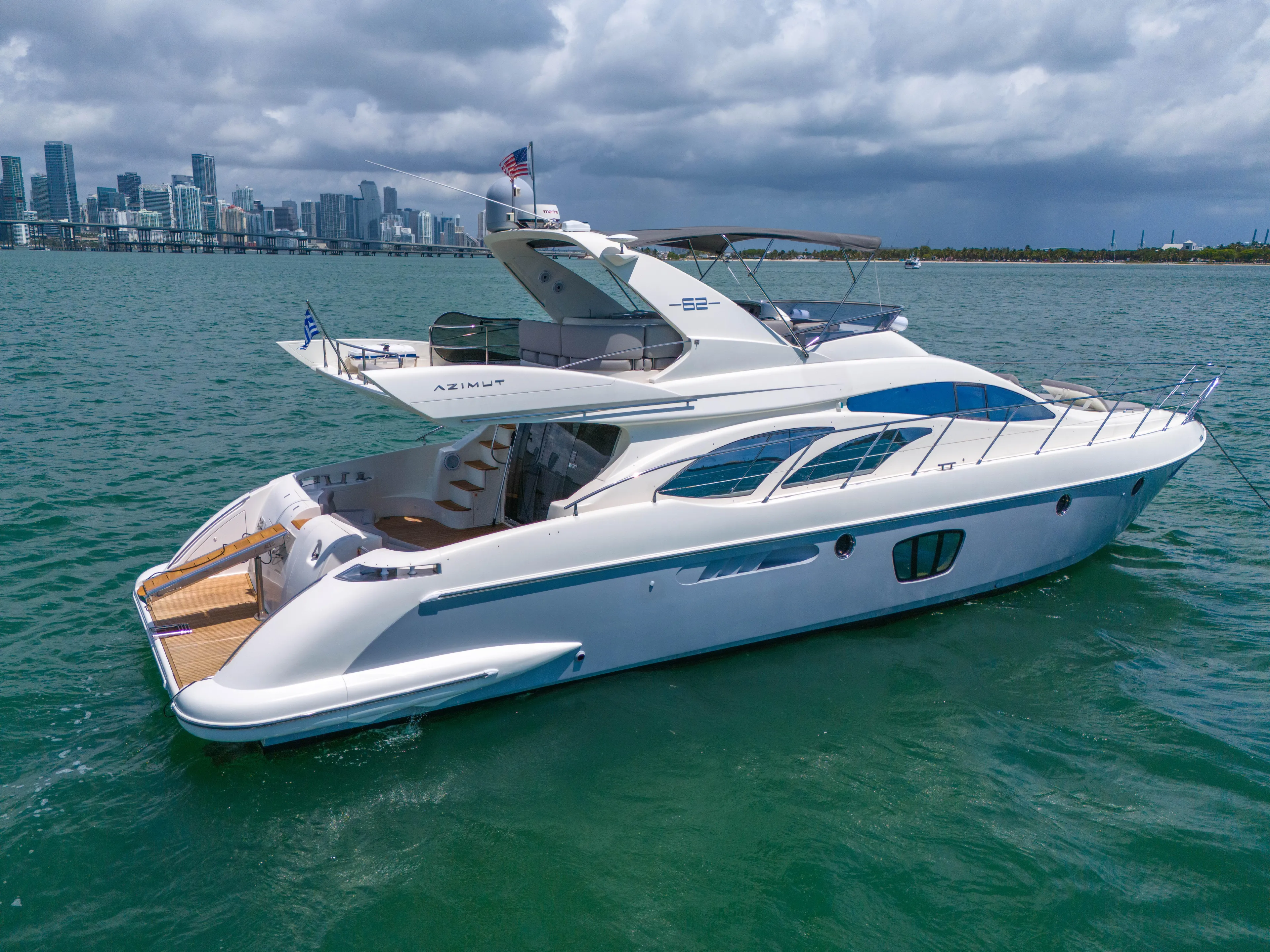 Bellami Too Yacht Photos Pics 2008 Azimut 62E yacht cruising near city skyline under cloudy skies.