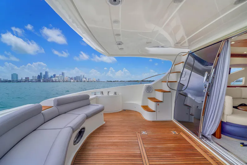 Bellami Too Yacht Photos Pics Luxurious 2008 Azimut 62E yacht deck with city skyline view, featuring elegant seating and wooden flooring.