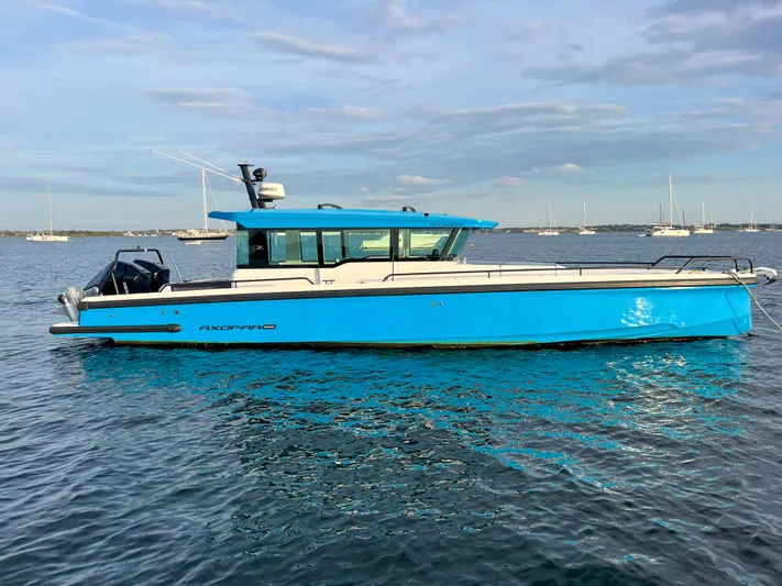 Tiny Dancer Yacht Photos Pics 2020 Axopar 37 XC boat on calm water, bright blue hull, clear sky background.