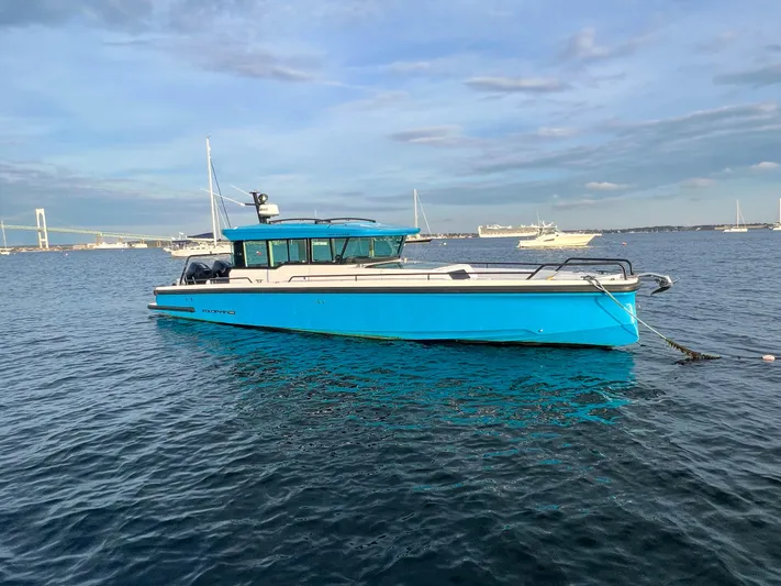 Tiny Dancer Yacht Photos Pics 2020 Axopar 37 XC boat in blue, anchored on calm water with a scenic background.