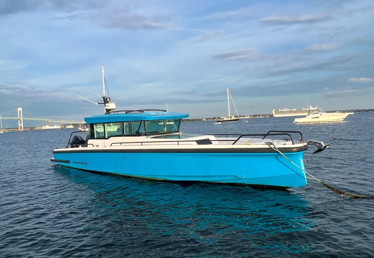 Tiny Dancer Yacht Photos Pics 2020 Axopar 37 XC boat in blue, anchored on calm water with a bridge in the background.
