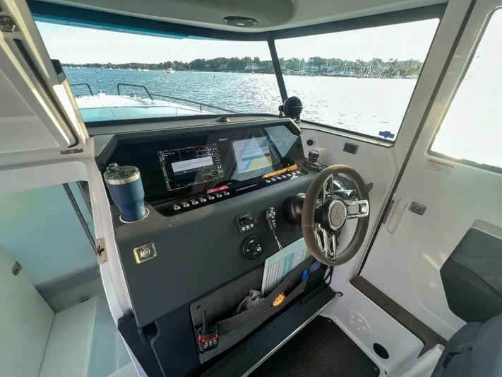 Tiny Dancer Yacht Photos Pics 2020 Axopar 37 XC boat cockpit with steering wheel and navigation screens, overlooking water.