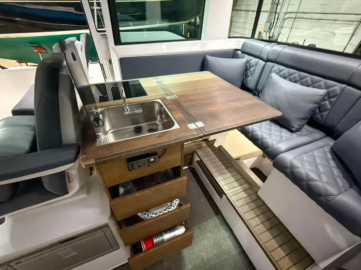 Tiny Dancer Yacht Photos Pics 2020 Axopar 37 XC interior with kitchenette, sink, and cushioned seating area.
