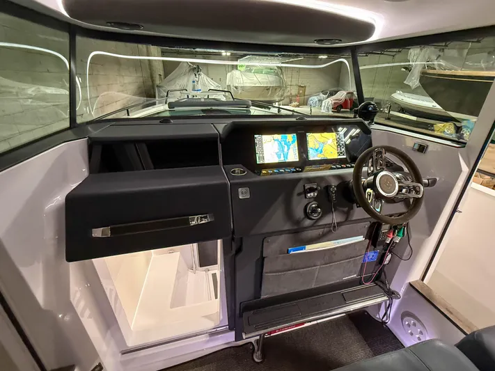 Tiny Dancer Yacht Photos Pics 2020 Axopar 37 XC helm with navigation screens and steering wheel in a modern cabin.