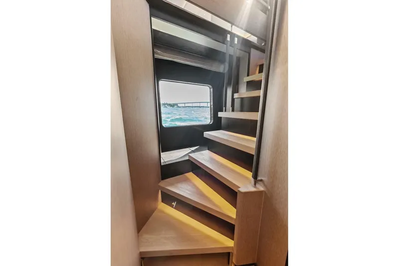 Fantasy Girl Yacht Photos Pics Interior staircase of 2025 Absolute 75 Navetta yacht with ocean view through window.