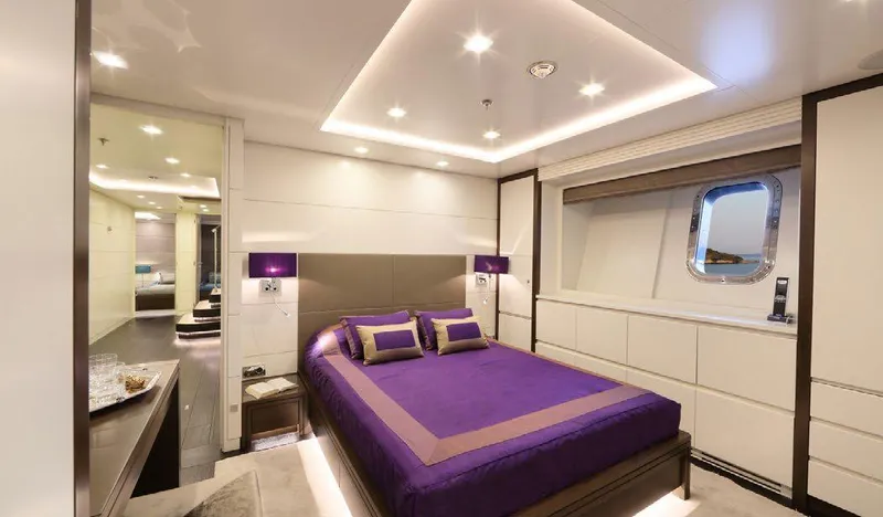  Yacht Photos Pics Luxurious bedroom interior on 1987 Benetti 50 CUSTOM yacht, featuring elegant purple bedding.