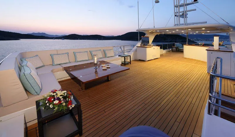  Yacht Photos Pics Luxurious deck of 1987 Benetti 50 CUSTOM yacht at sunset, featuring elegant seating and table.