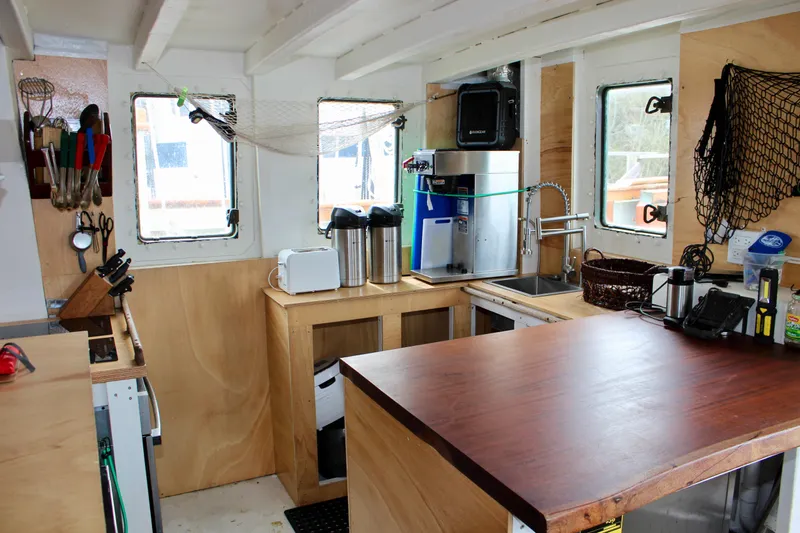 Hawaiian Chieftain Yacht Photos Pics Interior of 1988 Lahaina Welding Co. Square Topsail Ketch, featuring a compact wooden kitchen area.