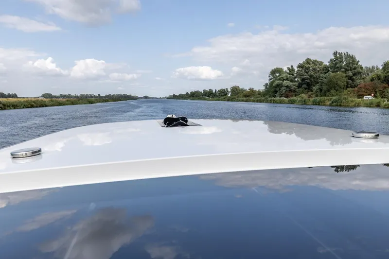  Yacht Photos Pics 2024 Vripack 42 Open Kuip boat cruising on a serene river under a partly cloudy sky.